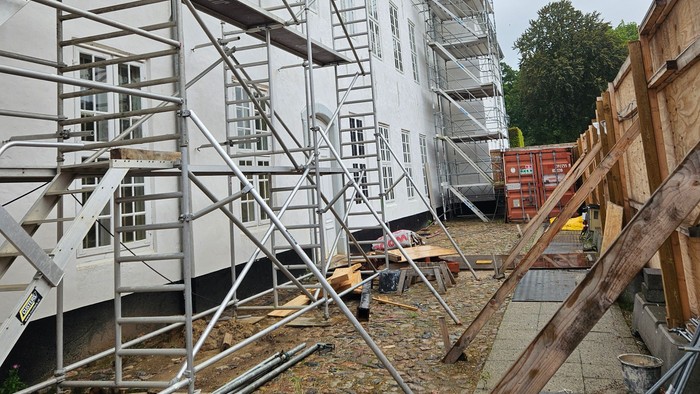 Byggeri med stillads omkring en fleretagers bygning under renovering eller nybyggeri.