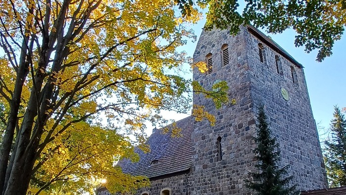 Dorfkirche Marienfelde umgeben von Bäumen mit Herbstlaub