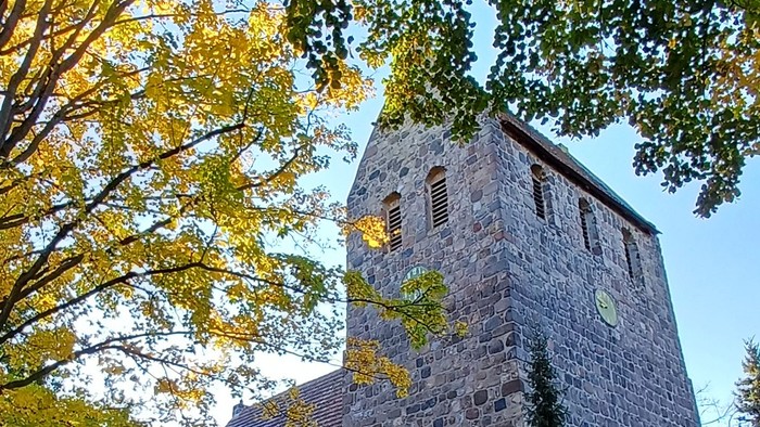 Dorfkirche Marienfelde umgeben von Bäumen mit Herbstlaub
