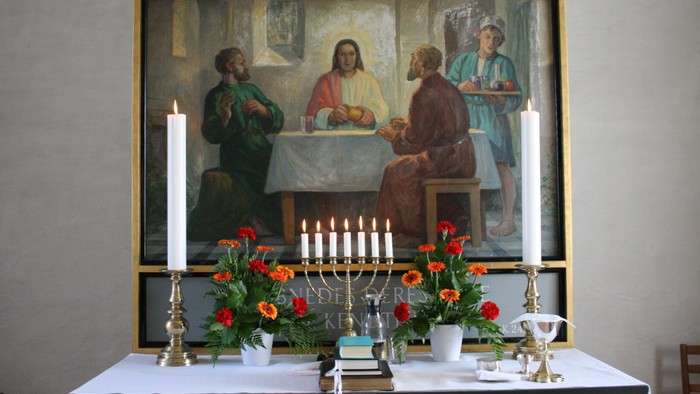 Billedet viser en altertavle med religiøse motiv og lysstake.