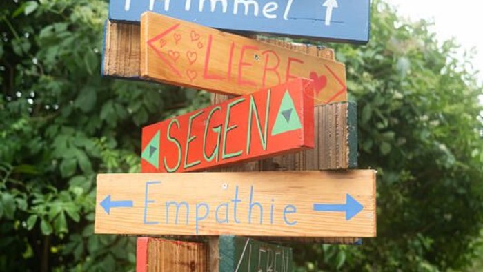 Bunte Holzschilder, die senkrecht gestapelt sind, zeigen positive deutsche und englische Wörter wie Hoffnung, Liebe und Freiheit.