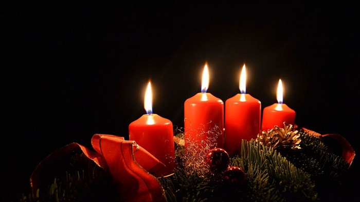 Vier brennende Kerzen in einem Adventskranz aus Tannenzweigen
