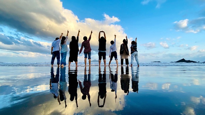 Eine Gruppe von Menschen feiert am Strand bei Sonnenuntergang
