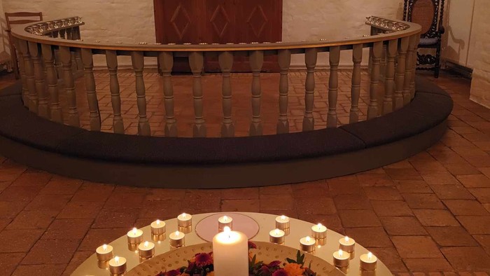 En altertavle med religiøse billeder og en lysestage med mange lyster.