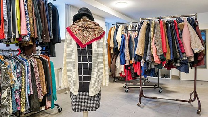 Ein Bekleidungsgeschäft präsentiert verschiedene Jacken, Schals und Accessoires auf Kleiderständern und Schaufensterpuppen.