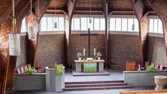 Ein moderner Wohnraum mit hohen Decken und großen Fenstern, eingerichtet mit Holz und grünen Akzenten.