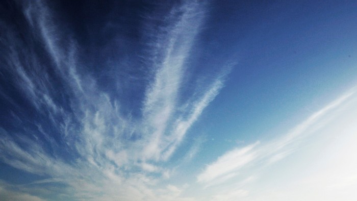 En klar himmel med spredte, hvide skyer.