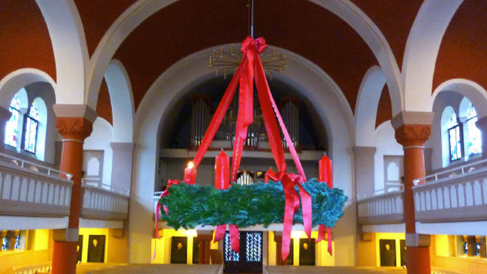 In der Kirche hängt ein großer Adventskranz von der Decke.