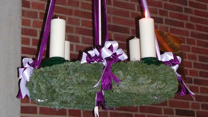 En hængende julekrans med lys og bænder