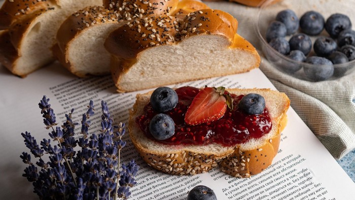 Selbstgemachter Toast mit Beeren, Marmelade und Samen, daneben frische Heidelbeeren und Lavendelzweige.