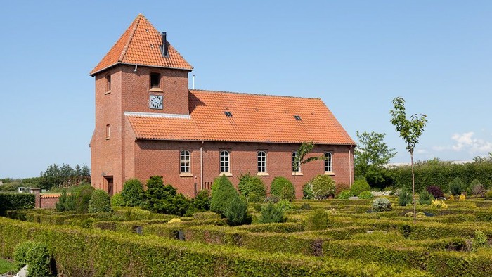 Røde kirke med klokketårn og grønne haver
