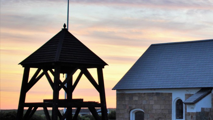En kirkegård med en klokketårn og en kirke ved solnedgang