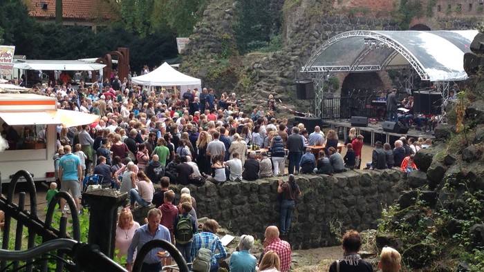 Das Foto zeigt das Kaiserpfalz Open Air mit Bühne im Hintergrund, Ständen seitlich und vielen zuhörenden Menschen