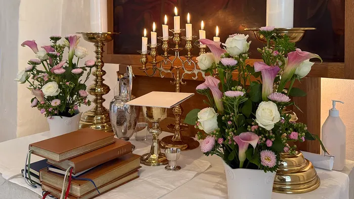 Alter med hvide og lilla blomster samt 7 tændte lys