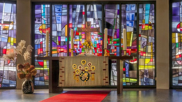 Kircheninneres mit Buntglasfenstern und rotem Teppichgang