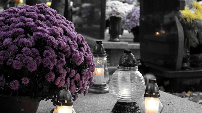 Violette Blumen und Kerzen auf Friedhof