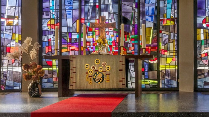 Kircheninneres mit Buntglasfenstern und rotem Teppichgang