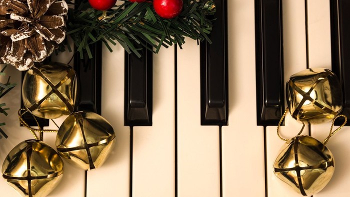 Guldjinglebells og grønne blad med røde bær på piano.