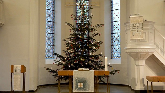 Weihnachtsbaum in der Kirche vor buntem Fenster