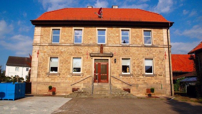 Zweistöckiges Steinhaus mit rotem Dach und Treppe zum Eingang