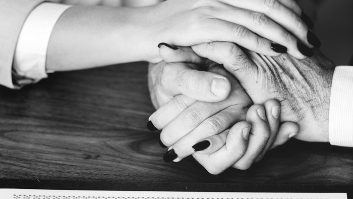 Paar, das sich während einer Zeremonie über einer Heiratsurkunde die Hände hält.
