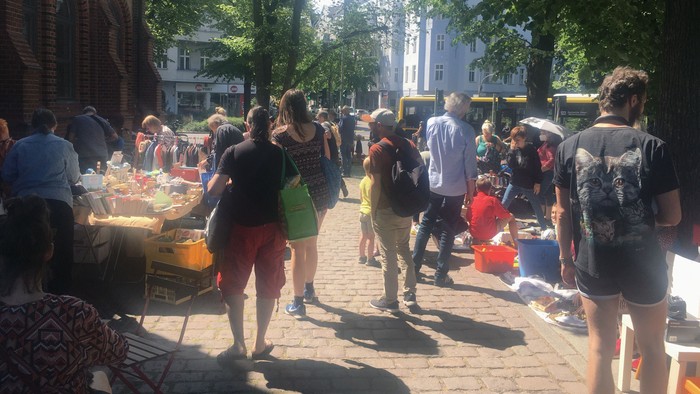Menschen auf belebten Straßenmarkt mit Ständen und Bäumen