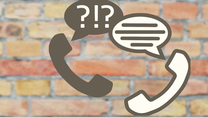 Zwei Telefone mit Sprechblasen vor Ziegelmauer