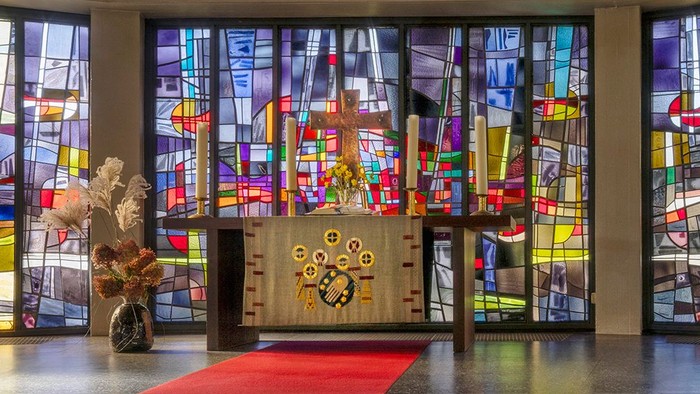 Kircheninneres mit Buntglasfenstern und rotem Teppichgang