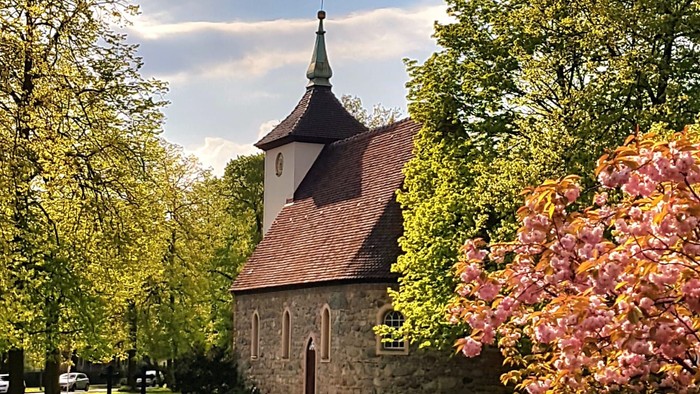 Kirchhof mit blühendem Garten und Kirschblütenbaum