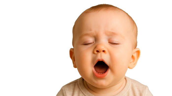 Et spæd barn åbner munden vidt og har lukkede øjne.
