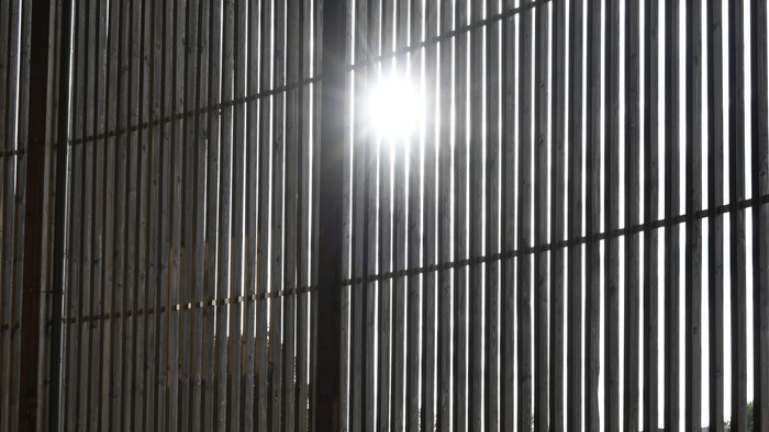 Das Bild zeigt einen Flur mit Gittern und Lichtstrahlen.