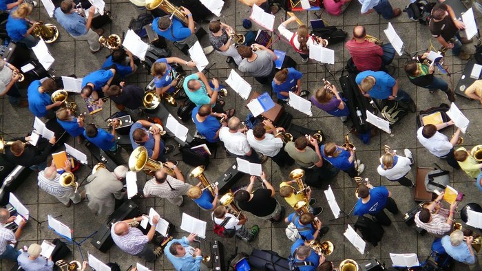 Eine große Gruppe von Musikern proben gemeinsam auf einem Platz.