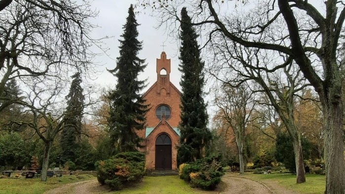 Kleine Kirche in Park mit Herbstlaub auf Schotterweg