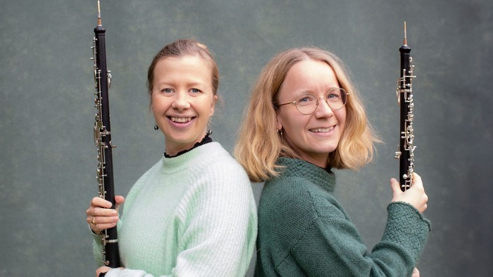 Maria Lundbæk og Freja Arendt, som danner Duo LunAre. De to står smilende med ryggen til hinanden og med hver deres obo i hænderne.