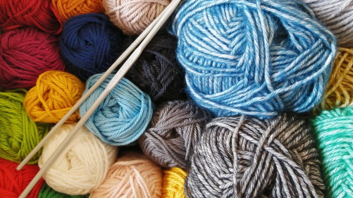 Bunte Garnknäuel und Stricknadeln kreativ für Handarbeitsprojekte arrangiert.
