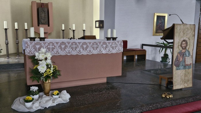 Ein Altar in einer Kirche mit Kerzen, Blumen und einem Kruzifix.