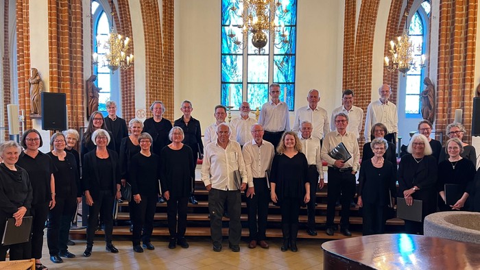 En gruppe mennesker i formelt tøj poser sammen inde i en stor kirke eller kapel.