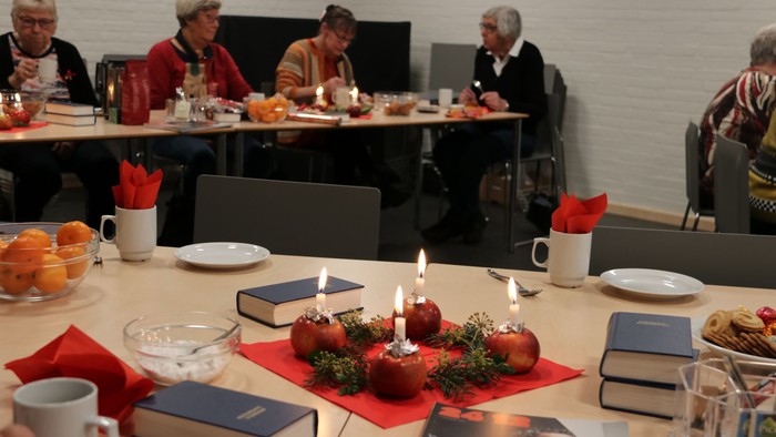 En gruppe mennesker sidder ved bord med mad og drikkevarer.