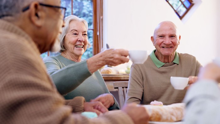 Fröhliche Seniorengruppe, die gemeinsam eine Mahlzeit in einer gemütlichen Essatmosphäre genießt.
