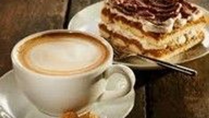 Kaffeetasse mit Inhalt neben einem Kuchenstück auf dem Teller
