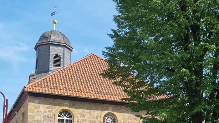 Kleine Kirche mit rotem Dach und grünem Rasen davor
