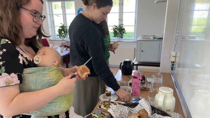 To kvinder tager brød fra bord den ene har lille barn på maven