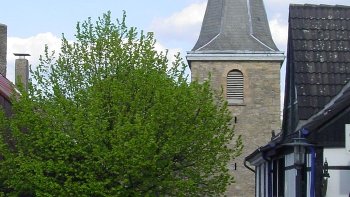 Kirchturm mit spitzem Dach über kleinen Ort