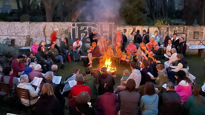 Die Gruppe versammelt sich um ein Lagerfeuer im Freien und genießt einen geselligen Abend mit Freunden und Familie.