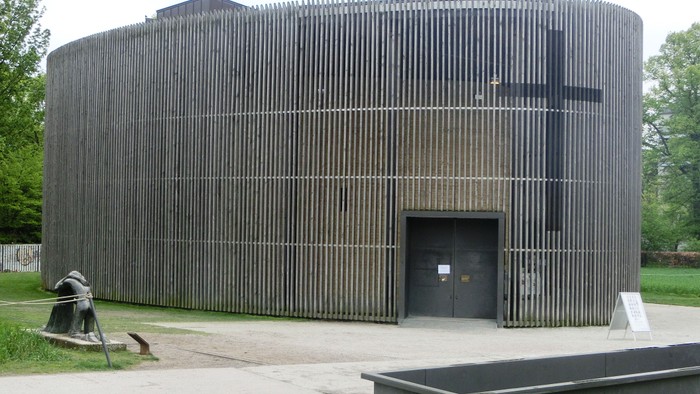 Das Bild zeigt eine moderne Kirche mit Holzwänden und einem großen Kreuz.