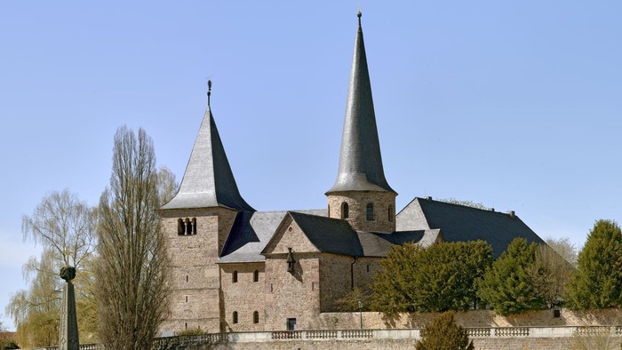 Historische Steinburg mit Zwillingstürmen und befestigten Mauern in einem gestalteten Innenhof.