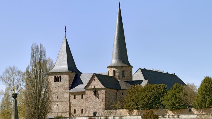 Historische Steinburg mit Zwillingstürmen und befestigten Mauern in einem gestalteten Innenhof.