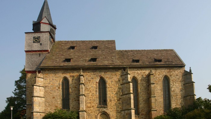 Außenansicht der evangelischen Kirche in Gottsbüren. Natursteinkirche mit hohen Spitzbogenfenstern.