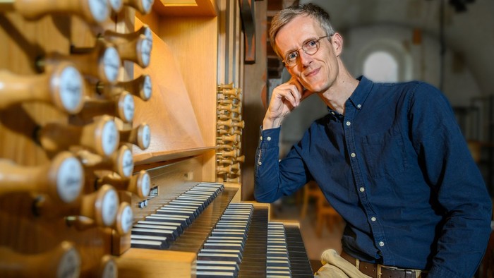 Mann in blauem Hemd spielt Orgel in Kirche