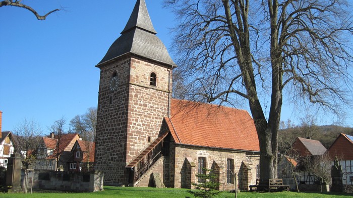 Außenansicht der evangelischen Kirche in Ehringen von der Südseite. Natursteingebäude mit rotem Ziegeldach und Turm mit schiefergedeckter Haube.